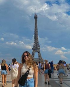 a woman standing in front of the eiffel tower with her hand on her hip