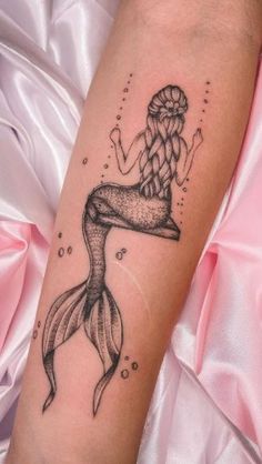 a woman's arm with a mermaid tattoo on it