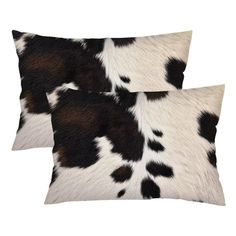 two black and white cowhide pillows on a white background, one with brown spots