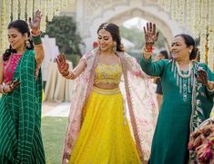 two women in green and yellow outfits are walking down the aisle with their hands up