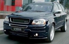 a black suv driving down a street next to tall buildings