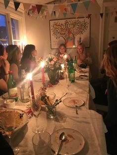 a group of people sitting around a table with food and candles in front of them