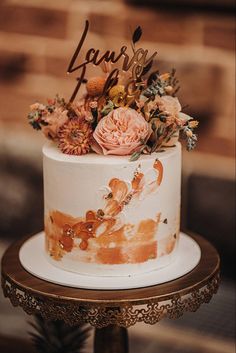 a wedding cake decorated with flowers and the word love on top is sitting on a table