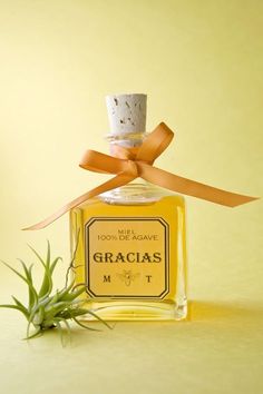 a bottle of gracias on a table with a plant in front of it