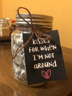 a mason jar filled with candy and a sign that says kisses for when i'm not around