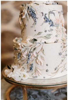 a three tiered white wedding cake with blue flowers