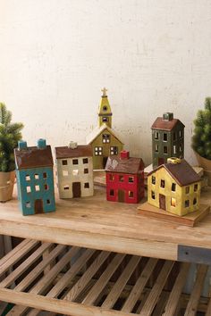 small houses are sitting on a wooden shelf next to potted plants and pine trees