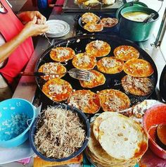 a table topped with lots of food next to bowls and pans filled with food