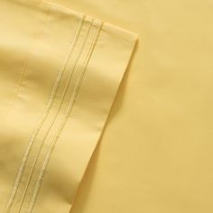 closeup of yellow sheets and pillowcases with white piping on the edges