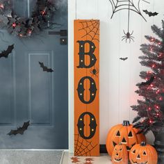 two pumpkins sitting in front of a door decorated for halloween with bats and boo's