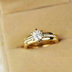 two gold wedding rings sitting on top of each other in a cardboard box with the lid open