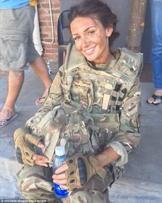 a woman in camouflage holding a water bottle