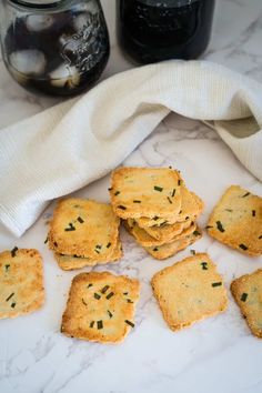 small crackers are arranged on a marble surface next to jars and a white towel