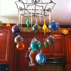 an assortment of blown glass ornaments hanging from a kitchen chandelier above a stove