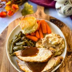 a white plate topped with meat, potatoes and green beans covered in gravy