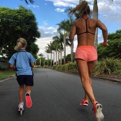 two people running down the road with one person on skateboard and another walking behind them