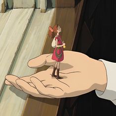 a hand holding a small doll in front of a person's hand