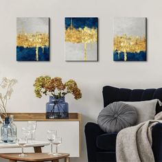 two paintings are hanging on the wall above a table with flowers and wine glasses in front of it