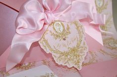 a pink and gold wedding card with a large bow on the front, sitting on a table