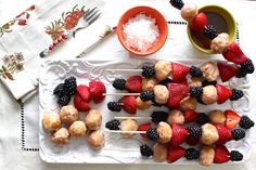 fruit skewers are arranged on a white platter