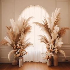 two vases filled with flowers and feathers on top of a hard wood floor next to a window