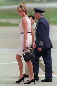 a woman in a white dress is walking next to an air force officer with a black handbag