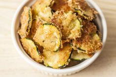 a bowl filled with fried zucchini on top of a wooden table