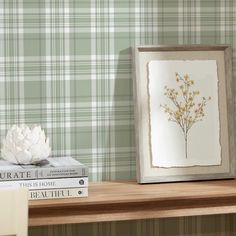 two books are sitting on a shelf next to a vase with flowers in it and a framed photograph