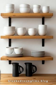 the shelves are filled with white dishes and black coffee mugs, which have been placed on top of each other