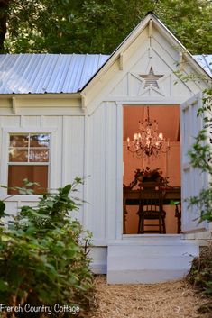 a small white house with a chandelier hanging from it's side window