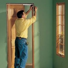 a man in yellow shirt and blue jeans working on a door frame with window panes