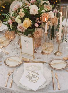 the table is set with gold and white plates, silverware, napkins, and candles