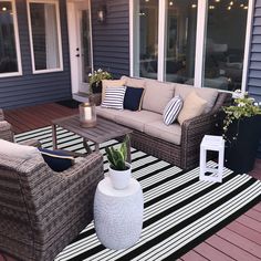 an outdoor living area with wicker furniture and potted plants on striped rugs