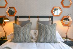 a bed with two pillows and some mirrors on the wall above it's headboard