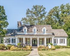 a white house with black shutters and trees in the background