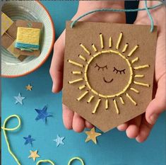 a hand holding a brown card with a yellow sun on it and stars around it