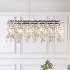 a crystal chandelier hanging from the ceiling in a living room with white walls