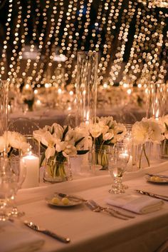 the table is set with white flowers and candles for an elegant dinner or banquet event