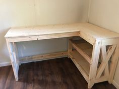 a wooden desk sitting on top of a hard wood floor next to a white wall