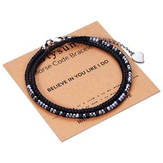 a bracelet with black beads and silver charms on top of a piece of brown paper