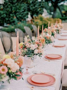 a long table with pink plates and flowers on it