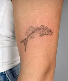 a fish tattoo on the back of a woman's left arm, with an outline of a fish