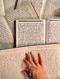 a person's hand on top of an open book with cursive writing