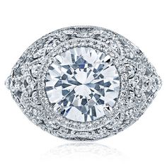 a diamond ring with an oval center surrounded by round brilliant cut diamonds, set in 18k white gold