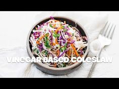 a bowl filled with coleslaw and carrots next to a fork