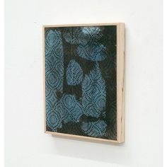 a blue and black painting mounted on a white wall next to a wooden framed object