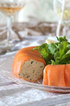 a glass plate topped with salmon and lettuce on top of a white table cloth