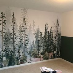 an empty room with trees painted on the wall and carpeted flooring in front of it