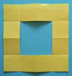 a piece of yellow paper that has been cut into squares and placed on a blue surface