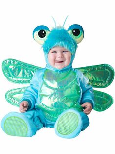 a baby dressed in a blue and green costume sitting on the ground with big eyes